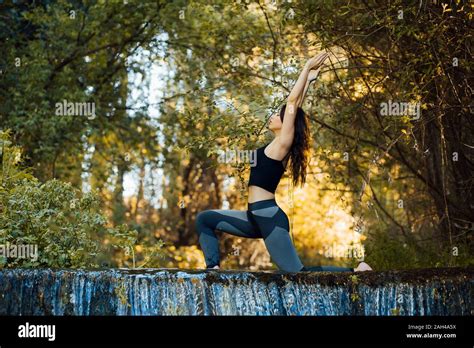 Young Woman Practicing Yoga On A Waterfall Bending Over Back Stock