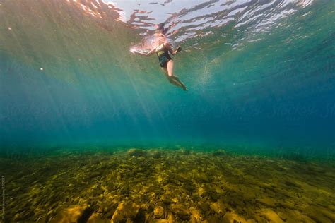 woman swimming underwater in clear summer lake by stocksy contributor jp danko stocksy