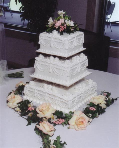 Three Tiered Cake Sitting On Top Of A Table Covered In White Frosting
