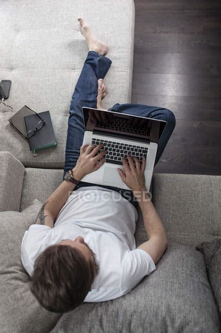Man Sitting On The Couch At Home And Using Laptop Top View — Style