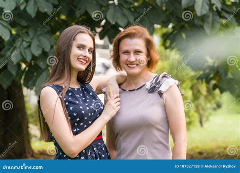 closeup portrait of adult daughter and mother outdoors pretty brunette and her mom are looking