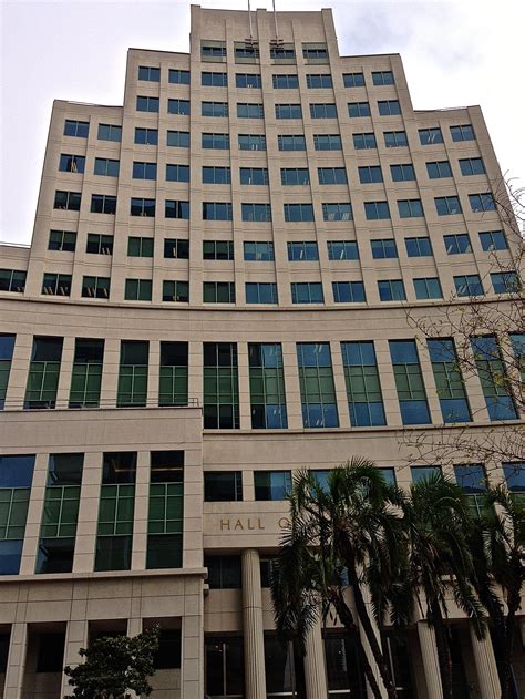 an office building with palm trees in the foreground and a clock at the top