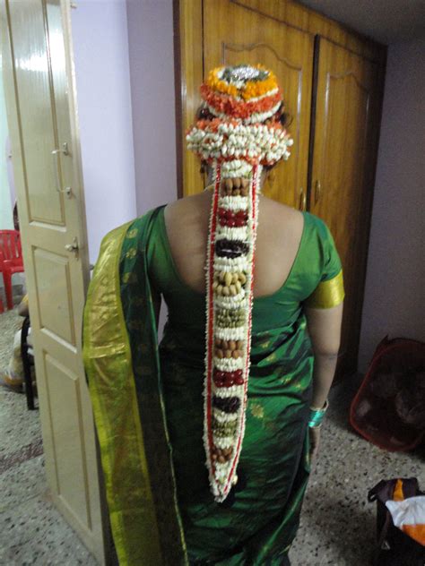 A Woman In A Green Sari With Flowers On It S Head Standing Next To A Door