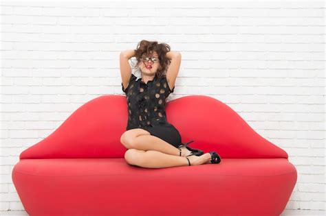 premium photo relaxed girl sitting on red sofa sexy model on leather couch beautiful