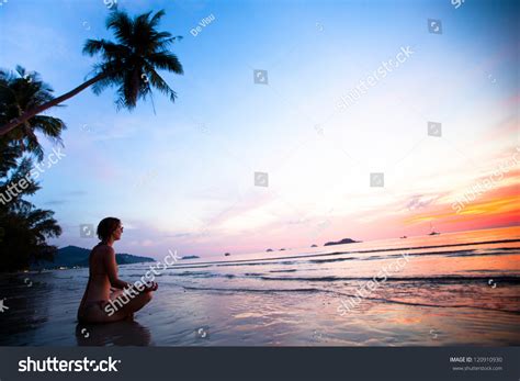 Beautiful Woman Doing Lotus Yoga Pose On The Beach Near