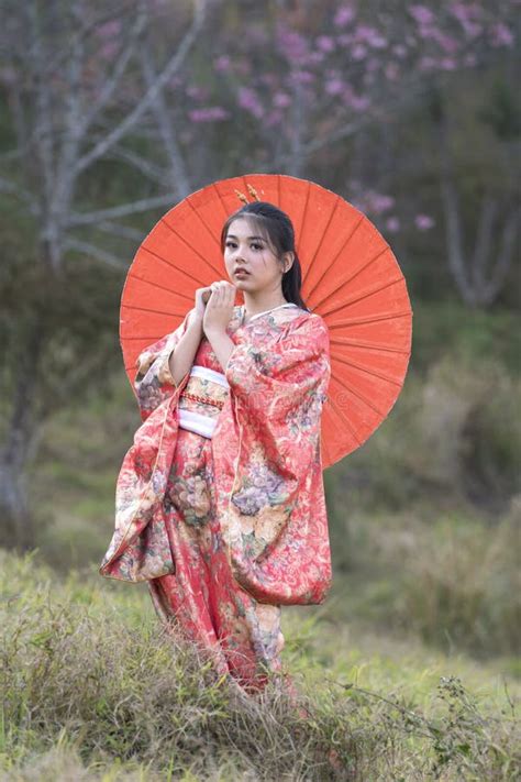 Attractive Asian Woman Wearing Kimono And Sakura Flowers Asian Girl In Red Dress In The Park