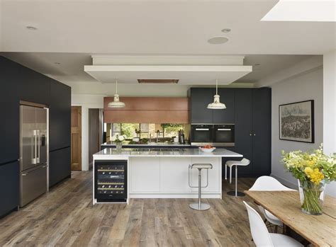 A Modern Kitchen With Wood Floors And White Counter Tops Black