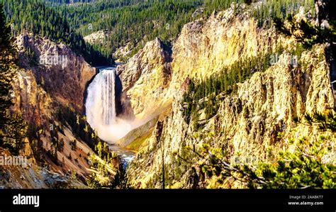 the upper falls of the yellowstone river flowing through the yellow and orange sandstone cliffs