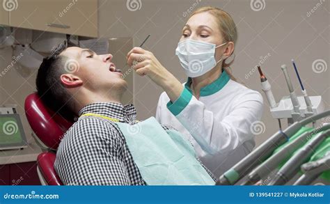 Female Dentist Examining Teeth Of Her Patient Working At Dental Clinic