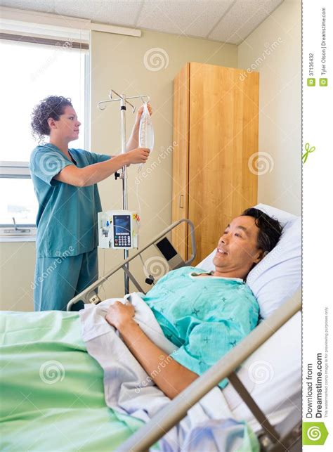 Nurse Adjusting Iv Drip On Rod With Patient On Stock Photography