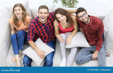 Cheerful Group Of Friends Laugh Sitting On The Couch Stock Photo