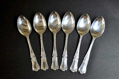 Six Silver Spoons Are Lined Up On A Black Surface