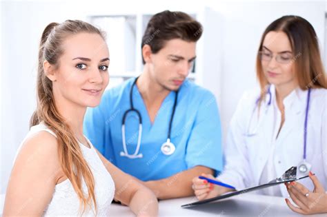 premium photo happy blond female patient next to a few doctors in hospital sitting at the table