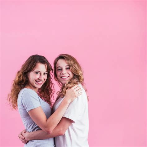Dos Amigas Abrazándose Contra El Fondo Rosa Foto Gratis