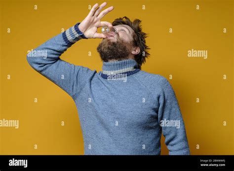 Shaggy Bearded Man In A Sweater Drinks Strong Alcohol From A Wineglass