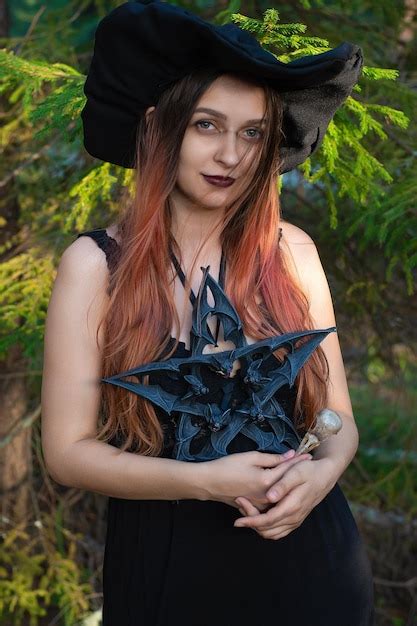 una niña disfrazada de bruja con un pentagrama alrededor del cuello está de pie en el bosque