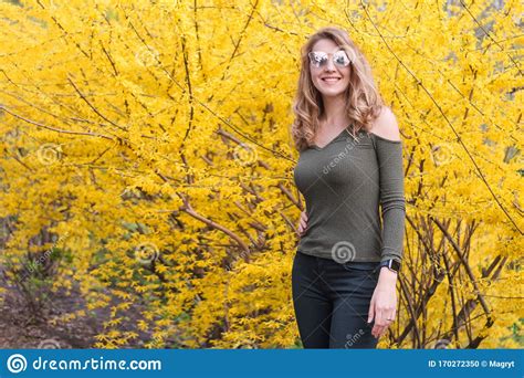 Young Blonde Woman Near Blossoming Yellow Trees In Spring Park On Sunny Day Beautiful Happy