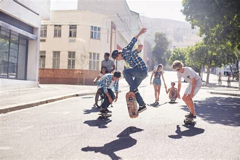 Teenage Friends Skateboarding On Sunny Urban Street Stock Photo