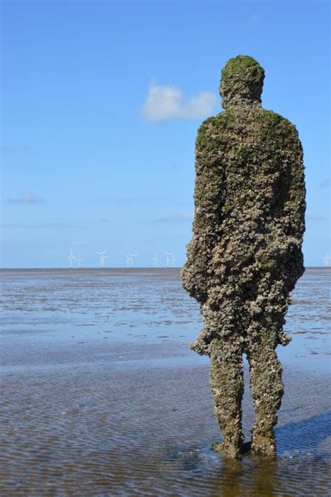 Young man lying on sandy beach. Antony Gormley's Another Place - Sculpture Writing
