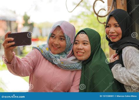 muslim woman and her teenager daughters happy asian indonesian sisters taking selfie with her