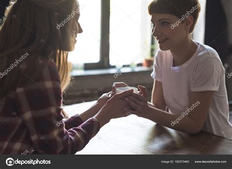 junges lesbisches paar hält tasse kaffee zusammen und lächelt stockfotografie lizenzfreie