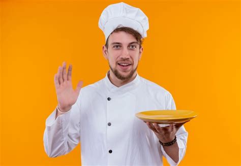 Um Jovem Chef Barbudo Sorridente De Uniforme Branco Segurando Um