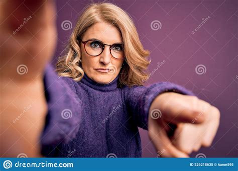 middle age beautiful blonde woman wearing sweater and glasses make selfie by the camera pointing
