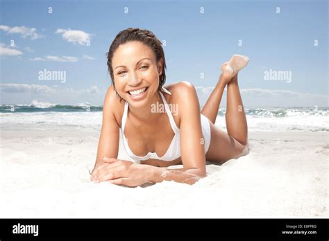 Portrait Of A Smiling Woman Lying On Beach Sunbathing Stock Photo