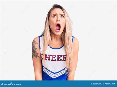 Young Beautiful Blonde Woman Wearing Cheerleader Uniform Angry And Mad Screaming Frustrated And