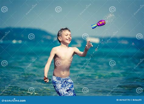 Enfant Gai Mignon Dans Le Swimware Jouant En Mer Avec Le Jouet Photo