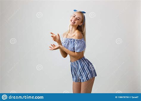 Joyful Blonde Girl In Summer Outfit Posing At Camera Showing Something