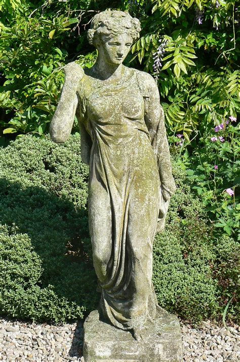 A Statue Is Standing In The Middle Of Some Bushes