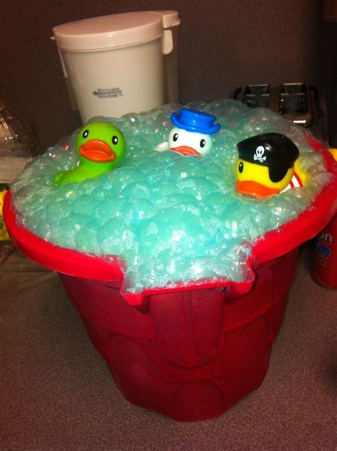 Three Rubber Ducks In A Red Bucket Filled With Foamy Bubbles And Water