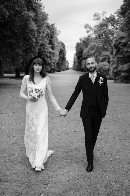 A Bride And Groom Holding Hands Walking In The Park Together Black And