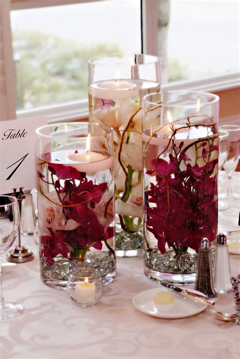 Two Vases Filled With Flowers On Top Of A Table Next To Candles And