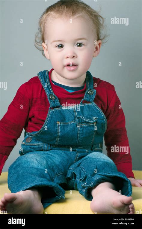 Portrait Of Smiling One Year Old Baby Boy In Red Top And Dungarees