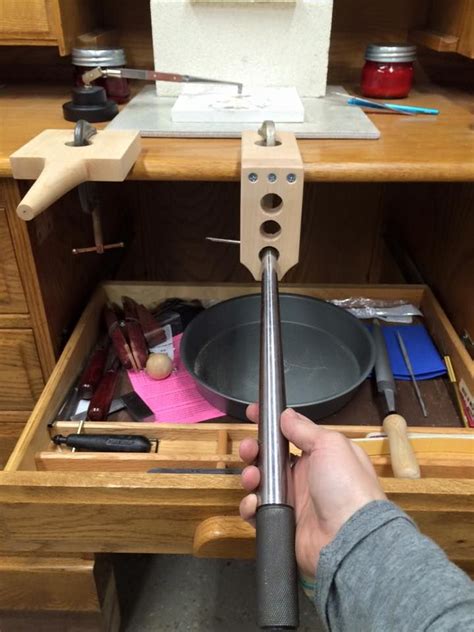 A Person Holding A Metal Object In Front Of A Wooden Cabinet With Tools