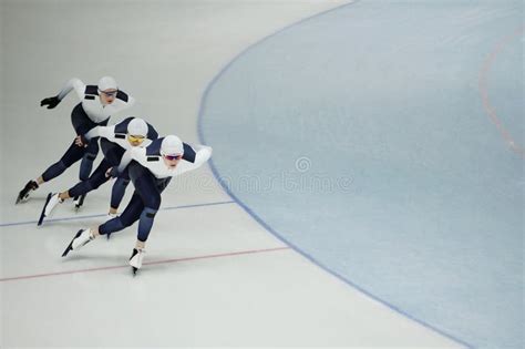 Row Of Three Young Active Athletes On Skates Sliding Along Ice Rink