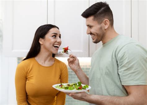 Happy Handsome Man Feeding His Pretty Girlfriend With Salad Stock Image