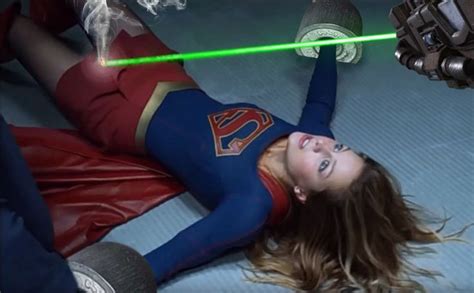 a woman laying on the ground with a green light saber in her hand and another person behind her