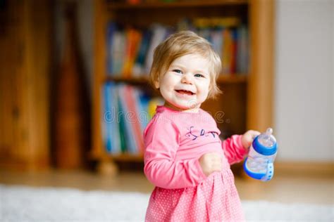 Cute Adorable Baby Girl Holding Nursing Bottle And Drinking Formula