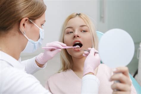 Premium Photo Woman Looking Into Mirror While Dentist Checking Her Teeth