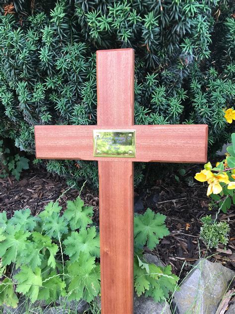 A Wooden Cross Sitting In Front Of Some Flowers