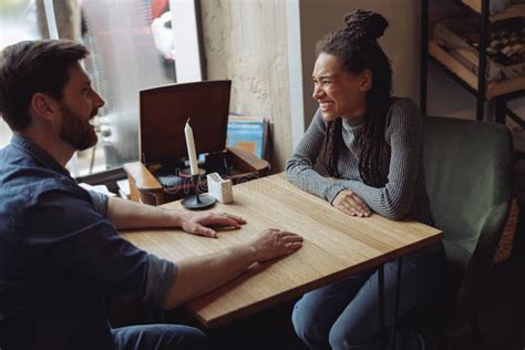 Cheerful Mixed Races Couple Laughing And Chatting At Table In Cafe