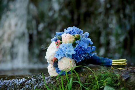 White And Blue Flowers Wedding Bouquet On A Waterfall Background Stock