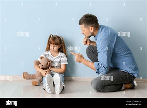 Angry Father Scolding His Little Daughter Sitting Near Color Wall Stock