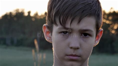 Portrait Of Sad Boy In A Wheat Field At Sunset Looking At The Camera