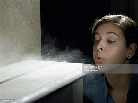 Young Woman Blowing Dust Off Shelf High-Res Stock Photo - Getty Images