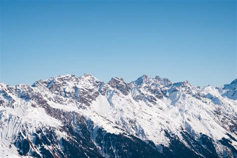 Snow Covered Rocky Mountains Under Clear Blue Sky · Free Stock Photo