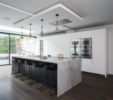 Modern Kitchen With White Waterfall Island Countertop And Black